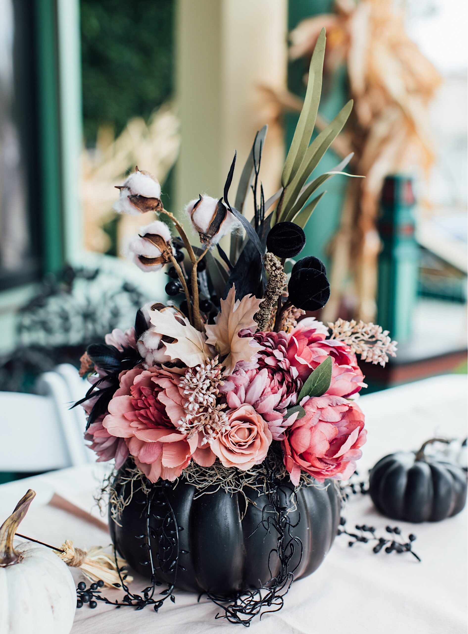 florals stuffed into black pumpkins as witch bridal shower decor outside of victorian haunted mansion by photographer Jessica Sofranko