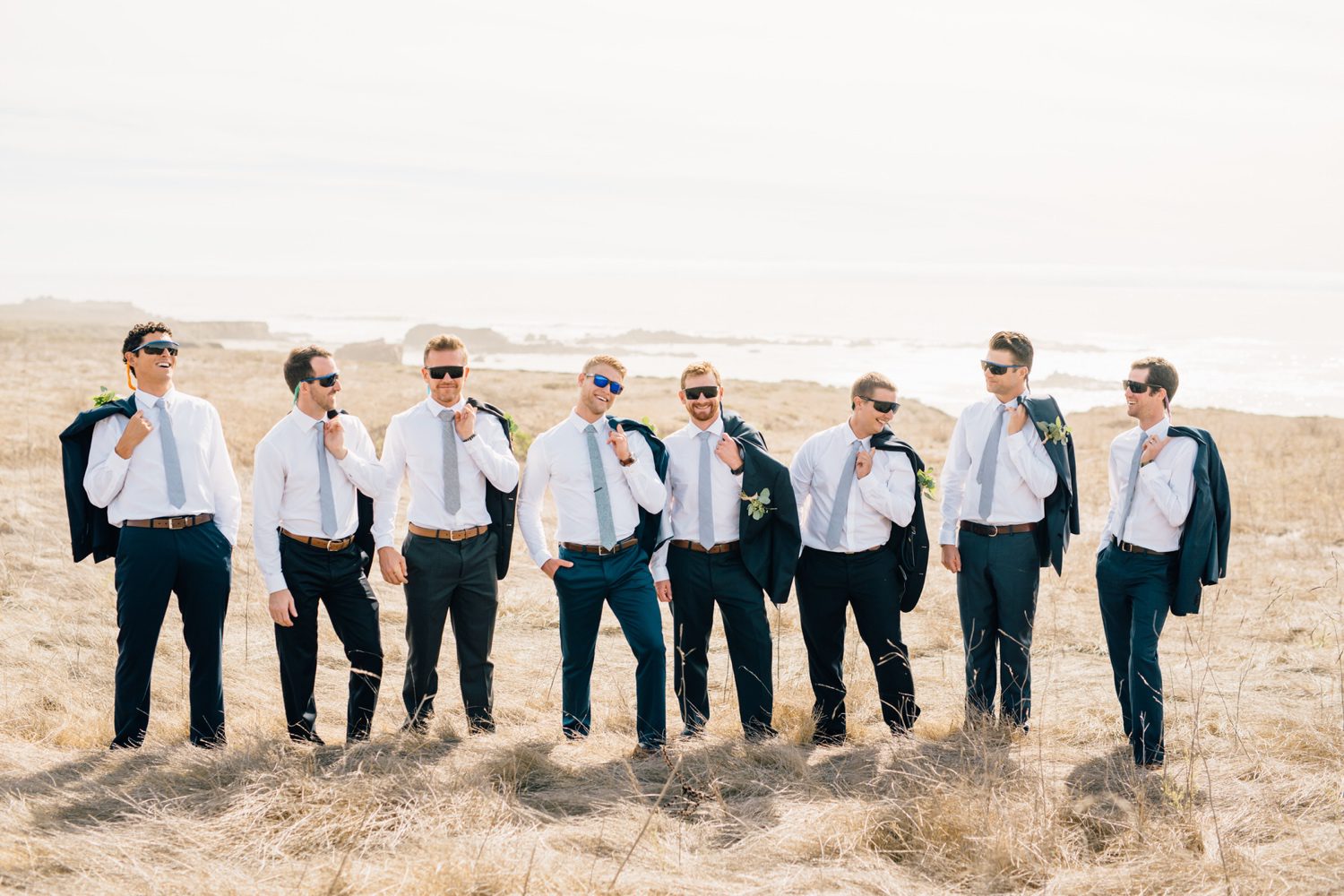 Groomsmen and Groom draping their suit coats over their shoulder with sunglasses
