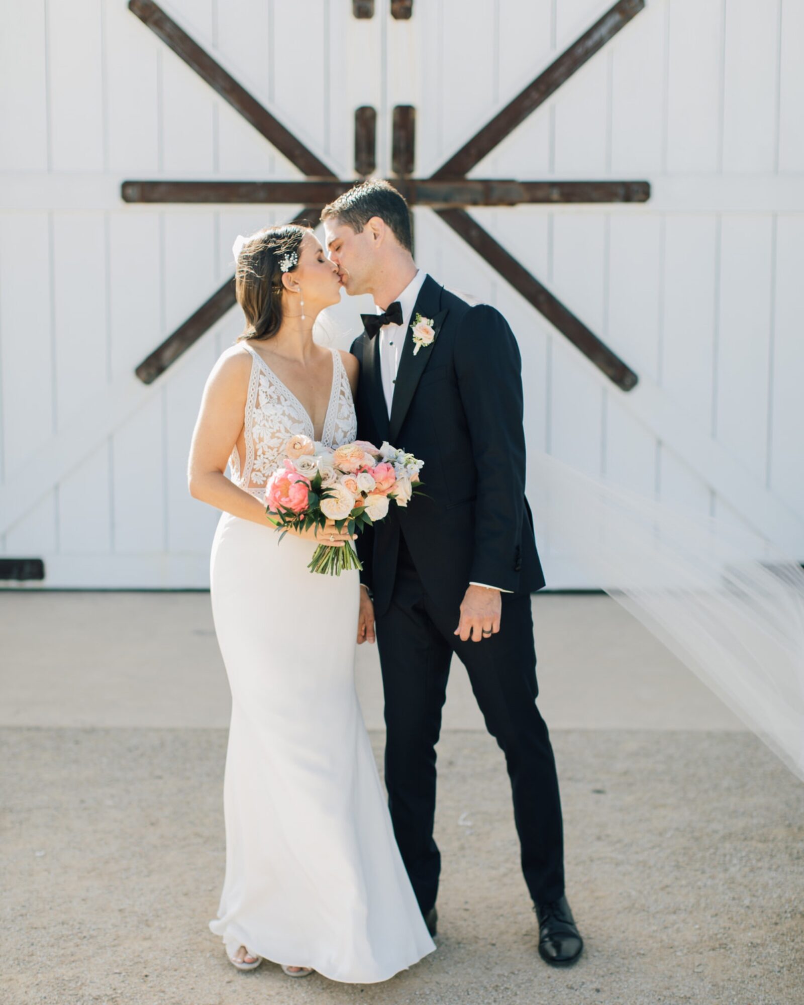 bride and groom kissing in front of at the White Barn Edna Valley photographed by san luis obispo wedding photographers jessica sofranko