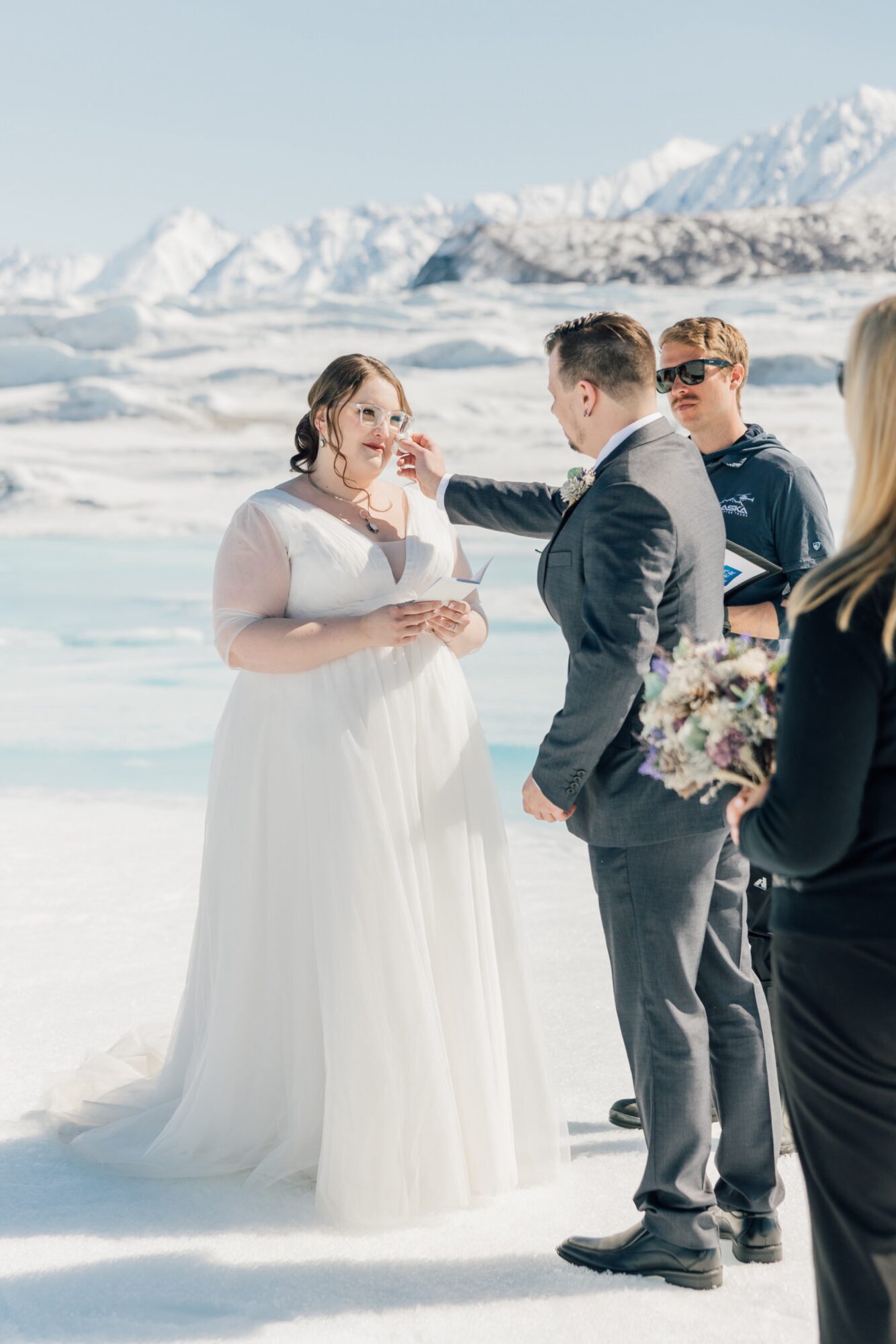 groom catching bride's tears during elopement ceremony on Knik Glacier by destination wedding photographer Jessica Sofranko