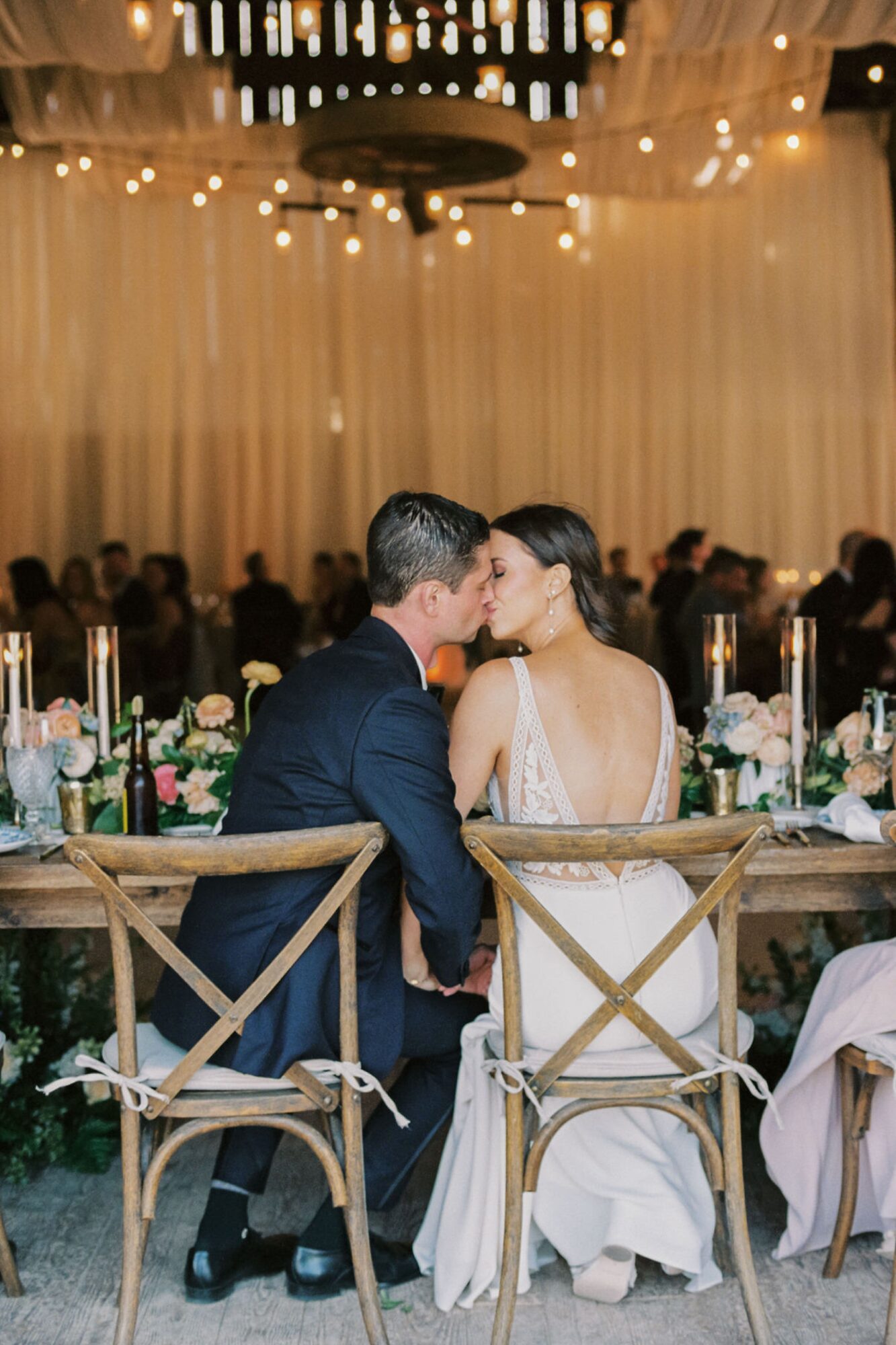Bride and groom kissing at reception dinner inside the barn at at the White Barn Edna Valley photographed by san luis obispo wedding photographers jessica sofranko