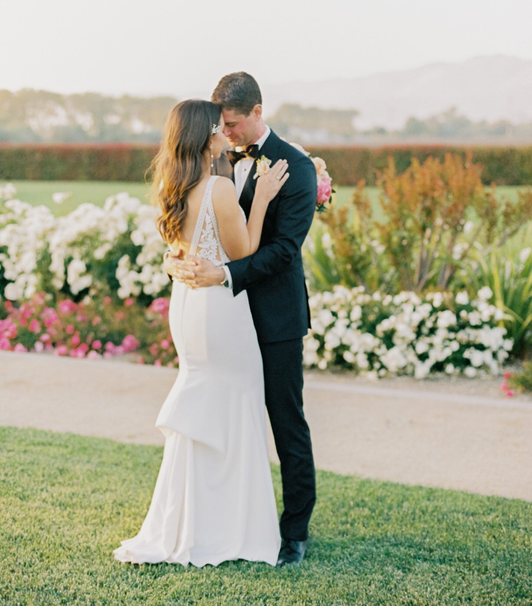bride and groom during sunset portraits in front of flowers at at the White Barn Edna Valley photographed by san luis obispo wedding photographers jessica sofranko