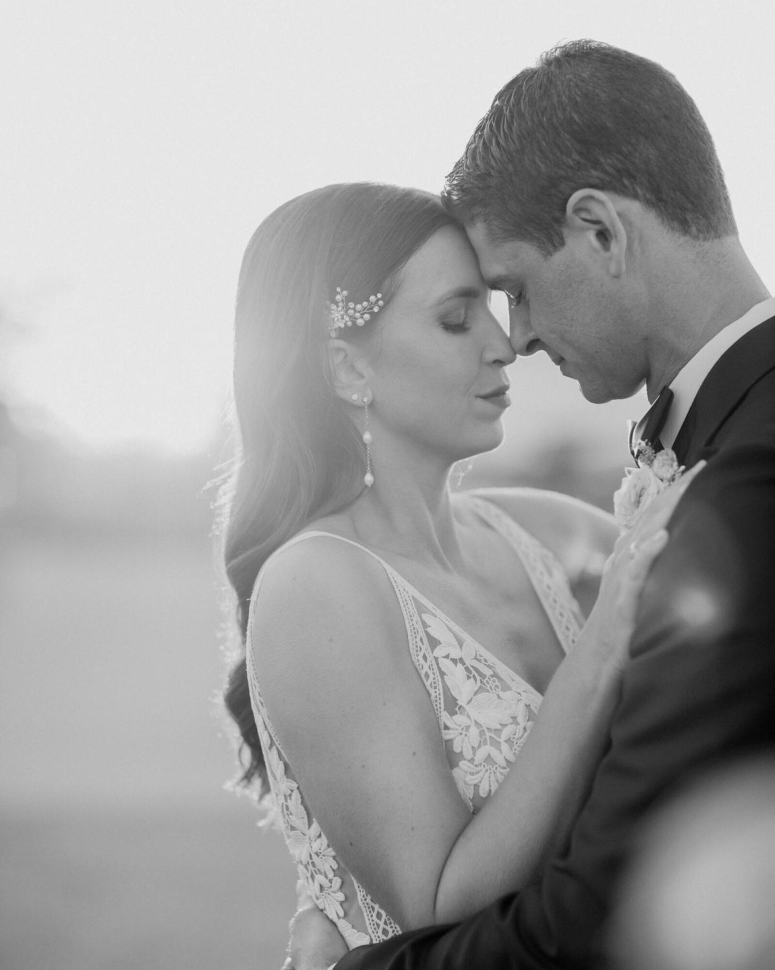 calm black and white photo of bride and groom nuzzling foreheads during sunset photos at at the White Barn Edna Valley photographed by san luis obispo wedding photographers jessica sofranko