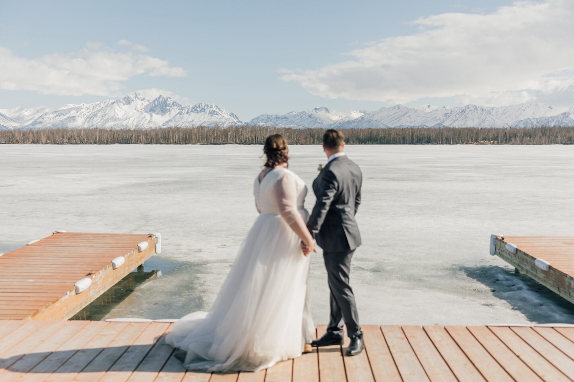 Bride and groom in front of frozen lake at Chop House at Lake Lucille in Wasilla Alaska