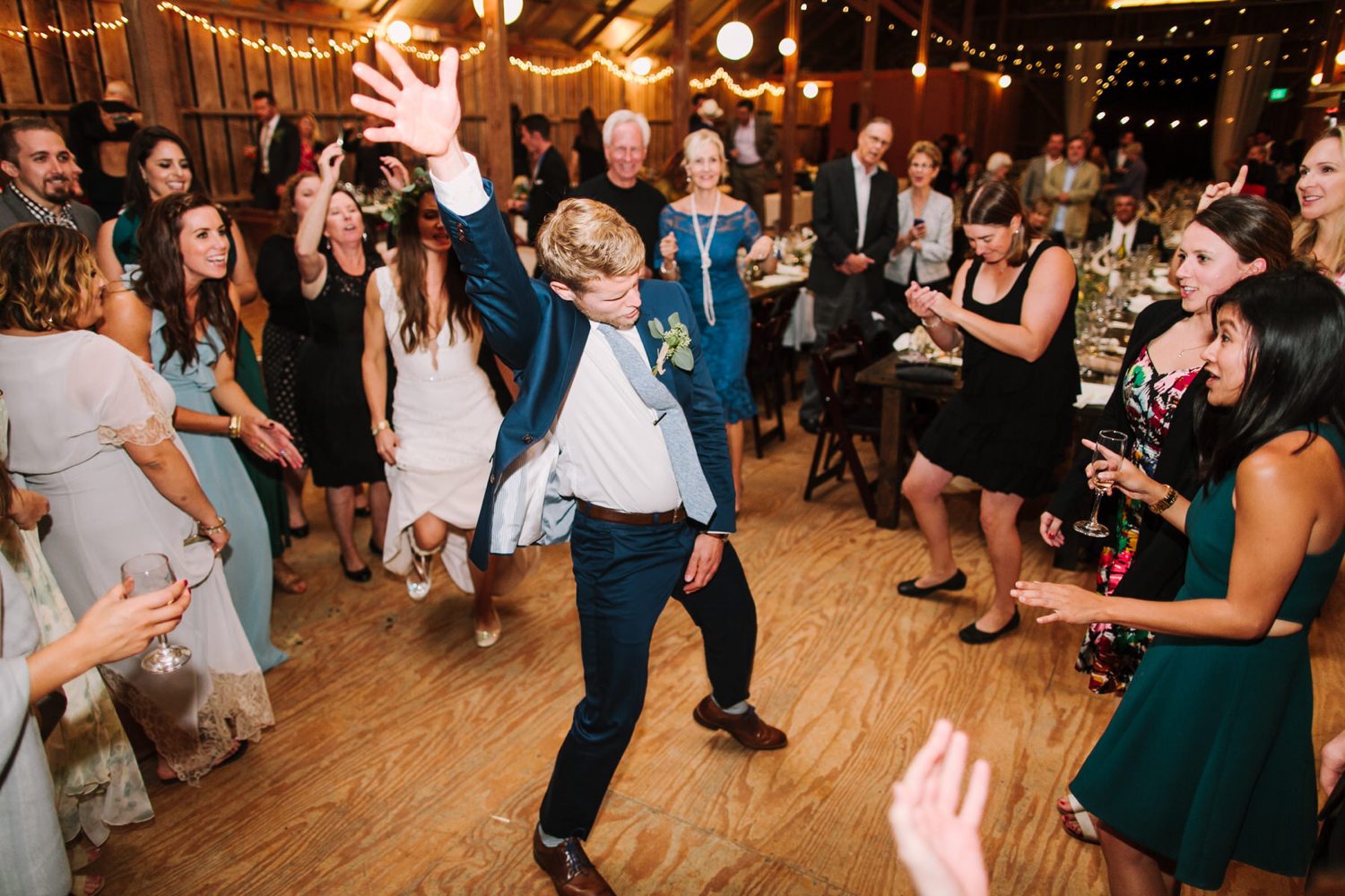 Groom surrounded by guests while he dances