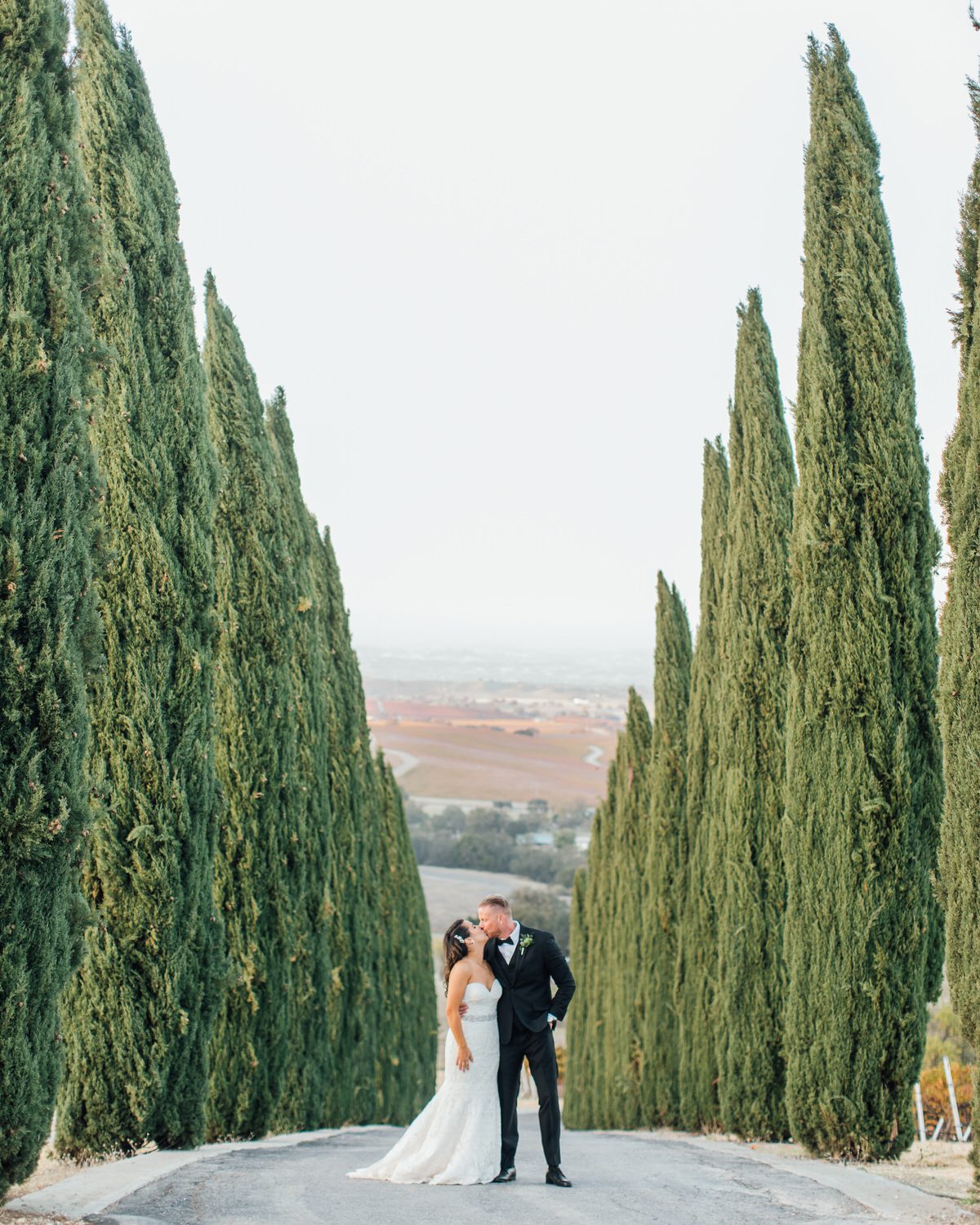 best san luis obispo winery wedding venues couple kissing in front of cyrpress trees by paso robles photographer jessica sofranko