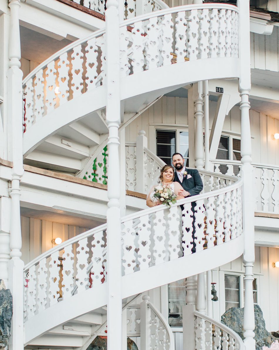 Best San Luis Obispo Iconic wedding venues Madonna Inn bride and groom on white heart staircase by photographer Jessica Sofranko