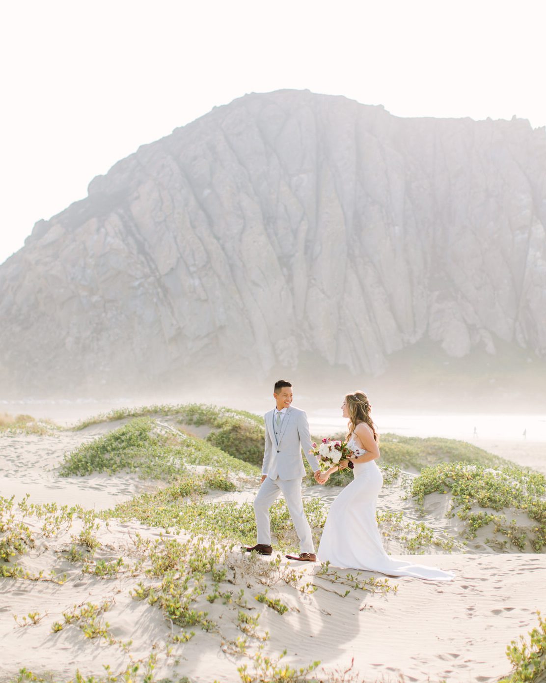 Best San Luis Obispo wedding venues at the beach in Morro Bay Windows on the Water bride and groom walking on the beach by photographer Jessica Sofranko